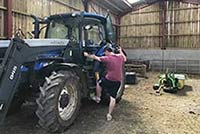 A farmer climbing into a tractor.